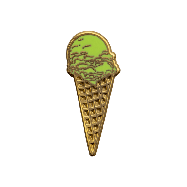A gold metal and green enamel pin of a pistachio ice cream waffle cone.