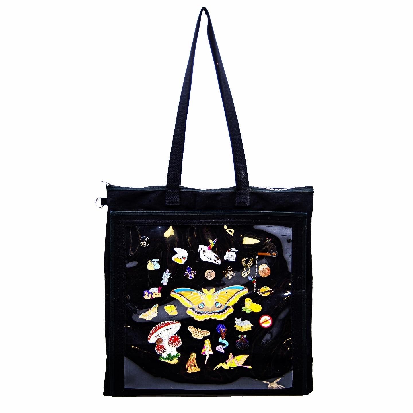 A black canvas Ita tote displaying enamel pins. The tote is big enough to hold vinyl records, a jacket, or a change of clothes.