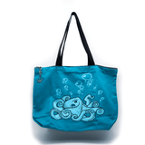 A turquoise tote bag featuring line art of an octopus and bubbles floating upwards. The zipper has a metal anchor shaped pull.