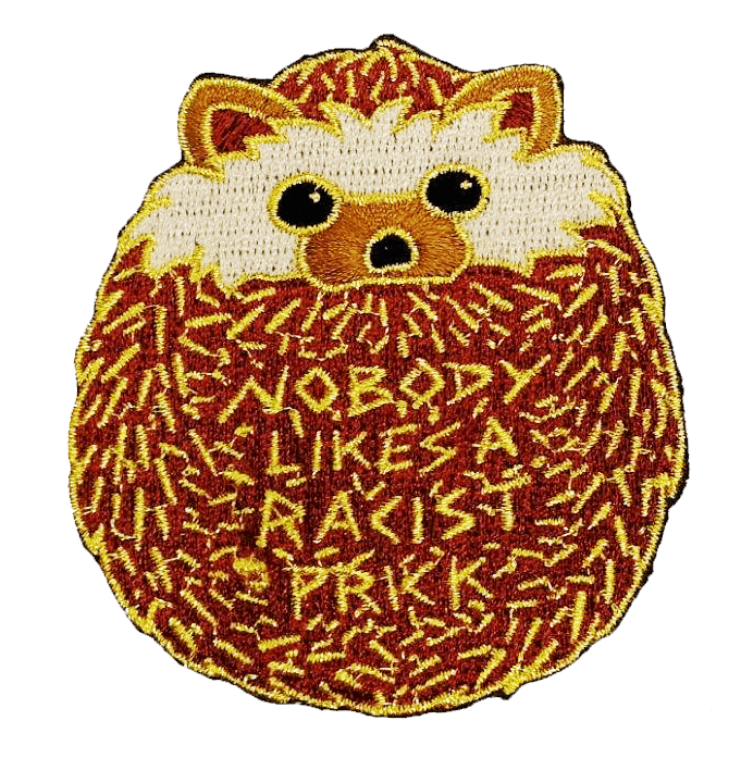 An embroidered patch resembling a rolled up hedgehog. Within the hedgehog's spines are the words "NOBODY LIKES A RACIST PRICK".