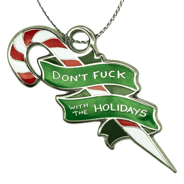 An enamel ornament of a red, white, and silver candy cane sharpened at one end, surrounded by a green banner that reads "DON'T FUCK WITH THE HOLIDAYS".
